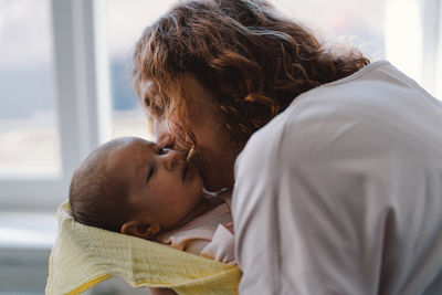 Portrait of happy mum holding infant child on hands.