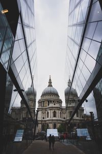 People walking in modern city against sky