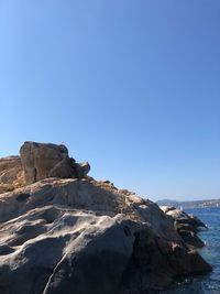 Rock formations in sea against clear blue sky