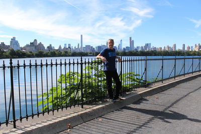 Rear view of woman walking on footbridge against sky