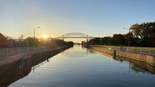 Bridge over river against sky during sunset