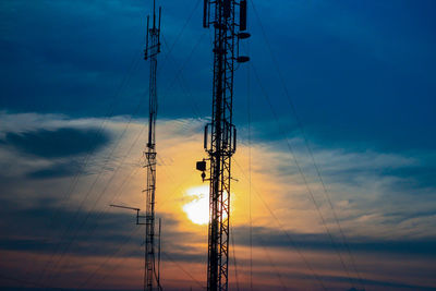 Low angle view of silhouette electricity pylon against sky during sunset