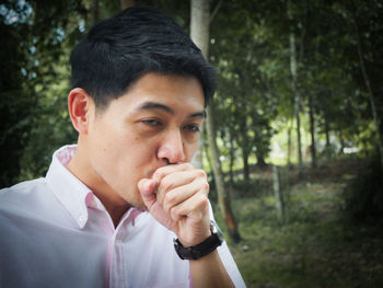 Man coughing against trees at forest