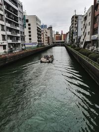 Canal amidst buildings in city against sky