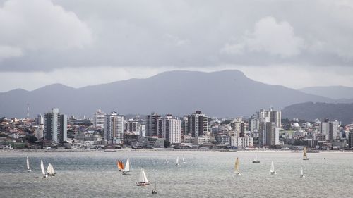 View of buildings by sea against cloudy sky