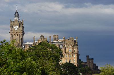 Tower amidst trees and buildings against sky