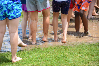 Low section of children standing in muddy puddle