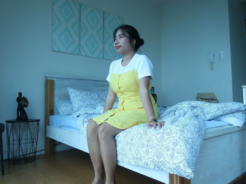 Young woman sitting on bed at home