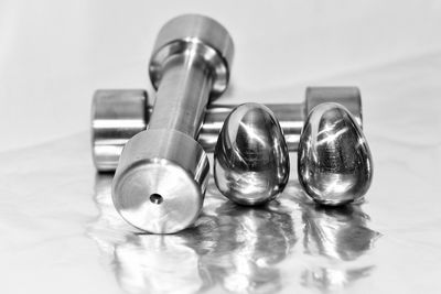 Close-up of silver eggs and dumbbells on table against gray background