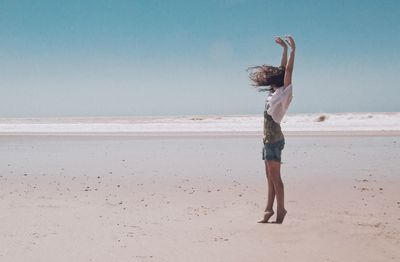 Full length of woman walking on beach against sky