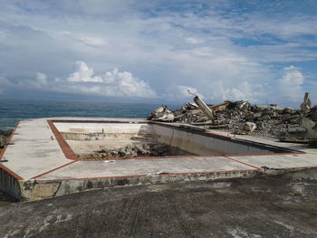 Abandoned built structure by sea against sky