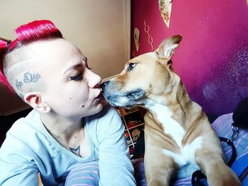 Woman kissing dog at home