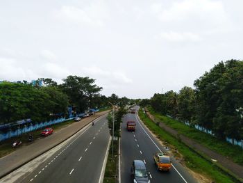 Cars on road by trees against sky