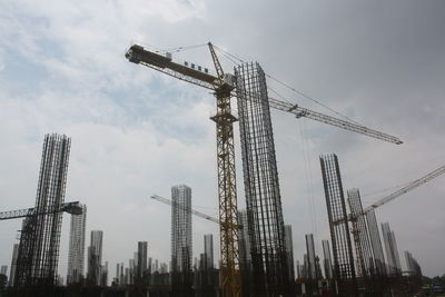 Low angle view of cranes against buildings
