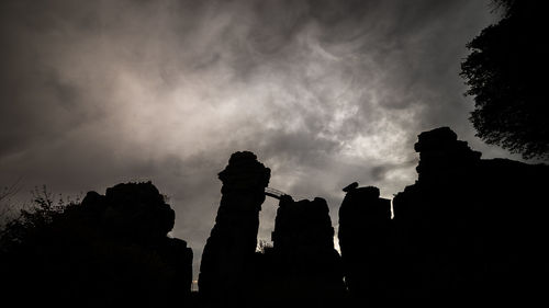 Low angle view of silhouette trees against cloudy sky