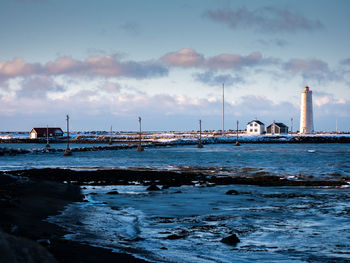 View of factory by sea against sky