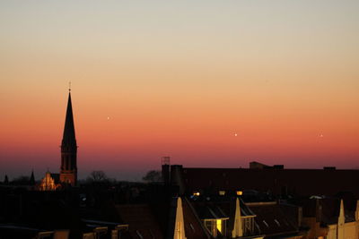 Silhouette cityscape against clear sky during sunset