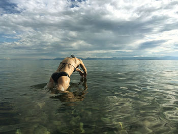 Man swimming in sea against sky