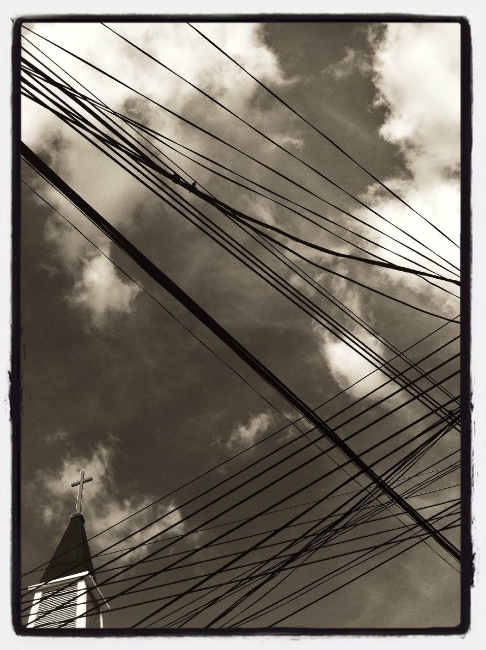 low angle view, sky, transfer print, cloud - sky, cloudy, built structure, auto post production filter, architecture, cloud, connection, day, building exterior, outdoors, part of, cable, no people, high section, overcast, tall - high, power line