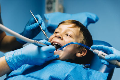 Cropped hands of dentists examining boy at clinic