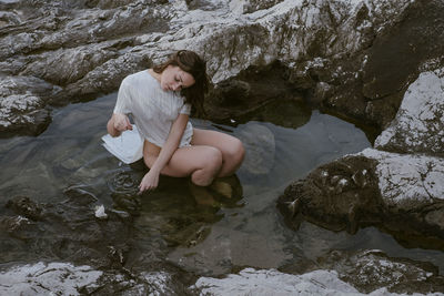 High angle view of young woman sitting on rock