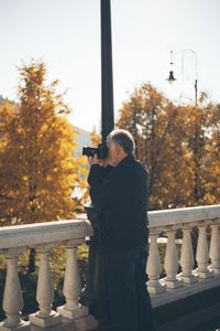 Rear view of man photographing through window