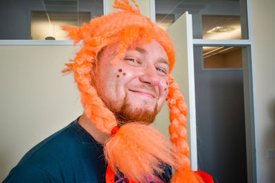 Portrait of mid adult man wearing orange wig at home