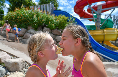 Side view of sisters eating potato chips on land during summer