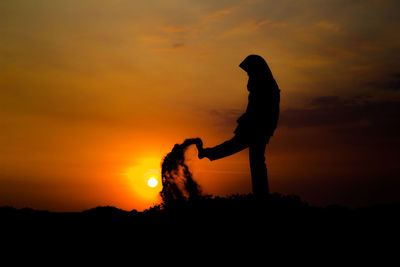 Silhouette man standing against orange sky during sunset