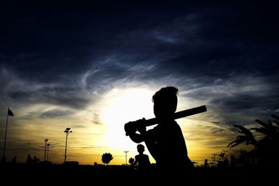 Silhouette man standing on street against sky during sunset