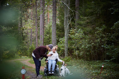 Male caretaker with disabled woman using mobile phone in forest