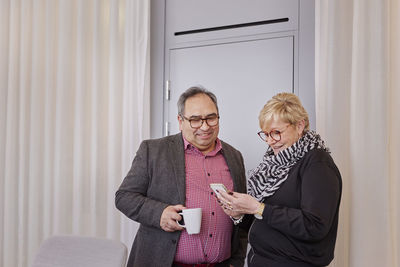 Portrait of smiling couple standing against wall