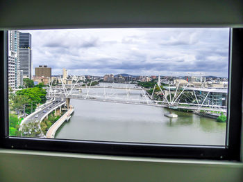 Bridge over river in city against sky