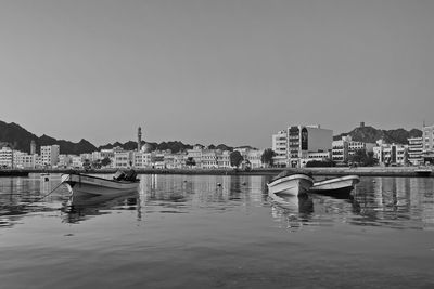 Fishing boats in city by buildings against clear sky