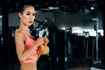 Young woman looking away while standing against blurred background