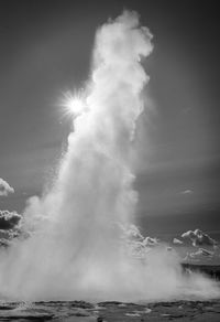 Sea waves splashing on shore against sky