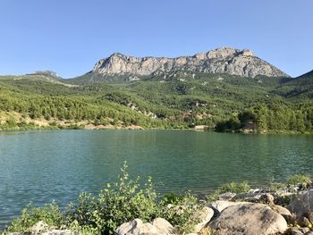 Scenic view of lake and mountains against clear blue sky