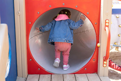 Rear view of girl walking on slide in playground