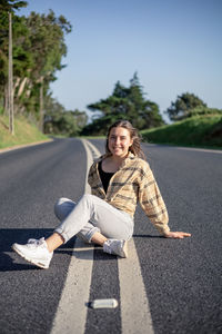 Portrait of young woman sitting on road