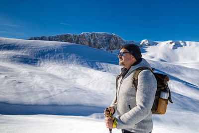 Portrait of young man standing on snow covered mountain