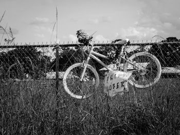 Abandoned bicycle on field against sky
