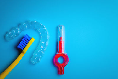 Toothbrush with transparent plastic aligners and interdental brush on blue background, dental clinic