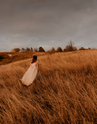 Side view of woman standing on field against sky