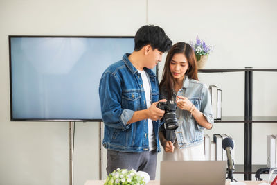 Portrait of young woman using mobile phone while standing at home