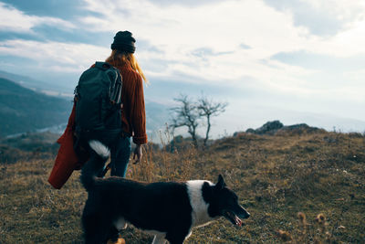 Rear view of dog standing on field against sky