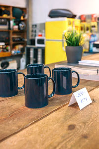 Close up of breakfast blue mugs over wooden counter in local store with industrial style decoration