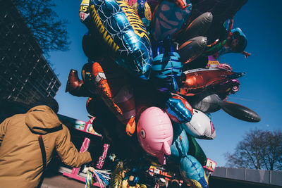 Rear view of man selling balloons against sky