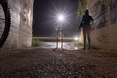 Rear view of man standing by wall at night