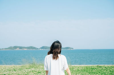 Rear view of man looking at sea against sky