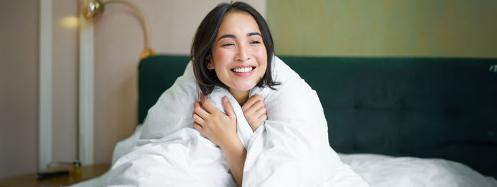 Portrait of young woman sitting on bed at home